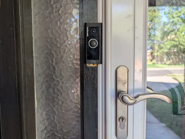 Video doorbell installed beside a glass storm door